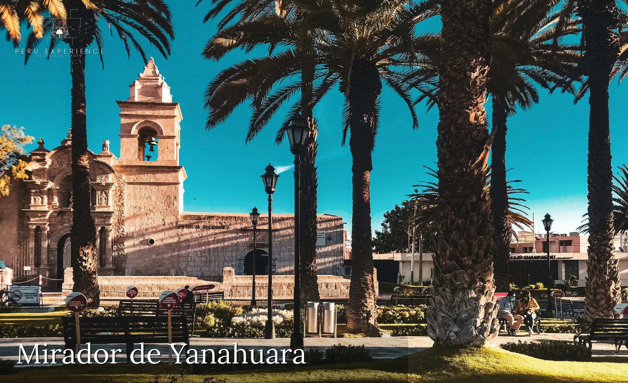 Igreja de San Juan Bautista no Mirador de Yanahuara, Arequipa, com torre sineira em pedra sillar branca, palmeiras imperiais e arcos coloniais — bairro tradicional fundado no século XVI