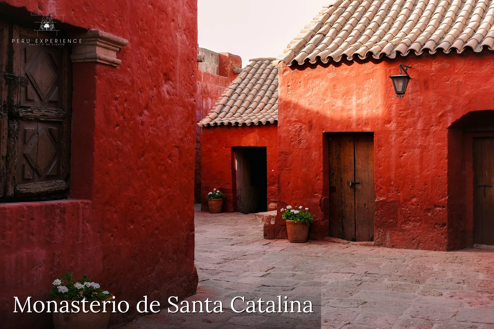 Paredes vermelhas características do Monasterio de Santa Catalina em Arequipa, com porta de madeira colonial e telhado de telha — ruas internas do convento dominicano clausurado por quase 400 anos