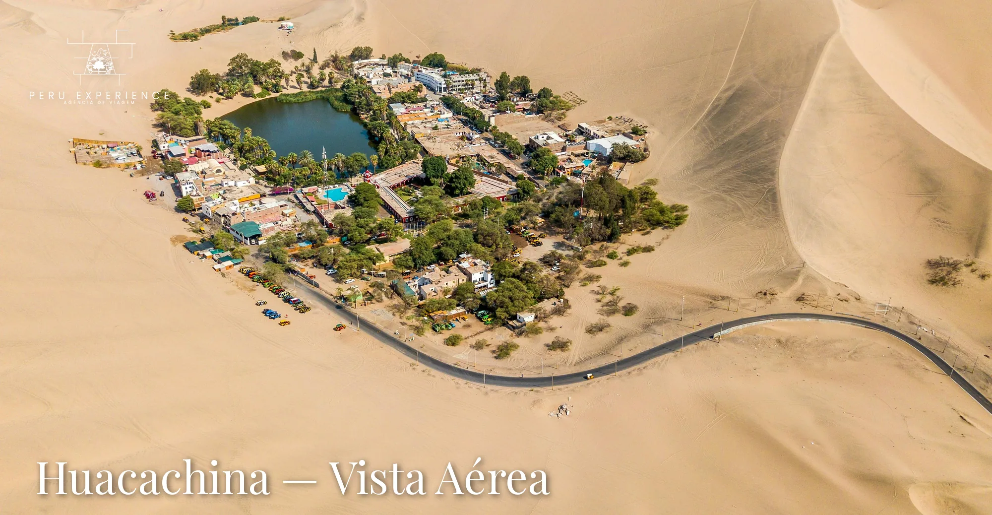Vista aérea panorâmica do oásis de Huacachina e das dunas que cercam a vila, com estrada de acesso ao deserto de Ica, Peru