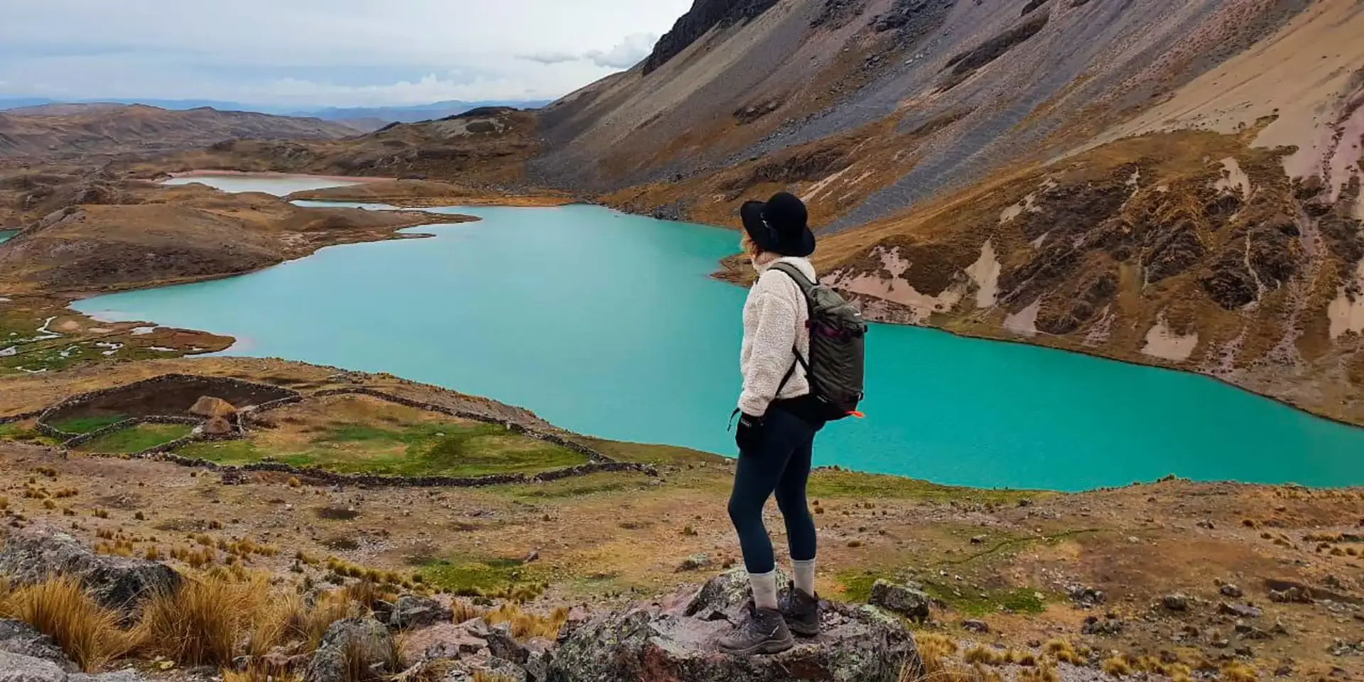 Lagoa de tom azul profundo entre as 7 Lagunas de Ausangate, com picos nevados ao fundo e vegetação de altitude, Cusco, Peru