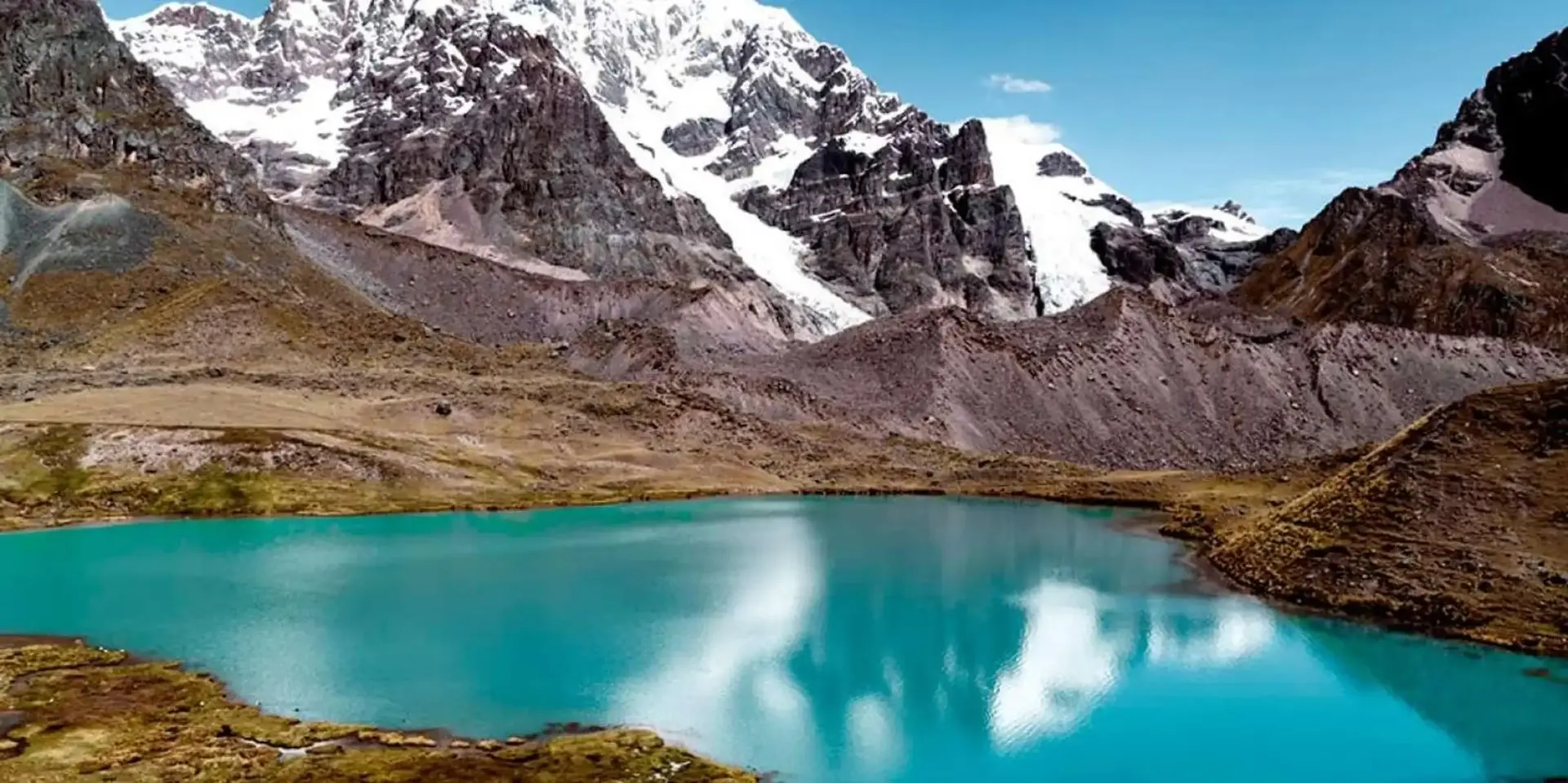 Caminhante em um mirante sobre uma das 7 Lagunas de Ausangate de águas turquesa, durante o trekking na Cordilheira de Vilcanota, Cusco, Peru