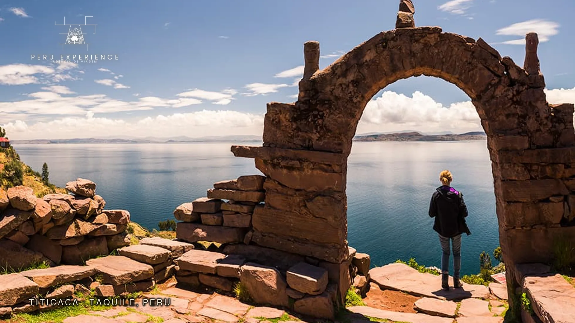 Arco de pedra na Ilha de Taquile com vista panorâmica do Lago Titicaca — o destino final da rota Cusco-Puno é o lago navegável mais alto do mundo a 3.812m, onde os tours de Uros e Taquile começam (combinação clássica de 3 dias com o Ônibus Turístico Cusco-Puno)