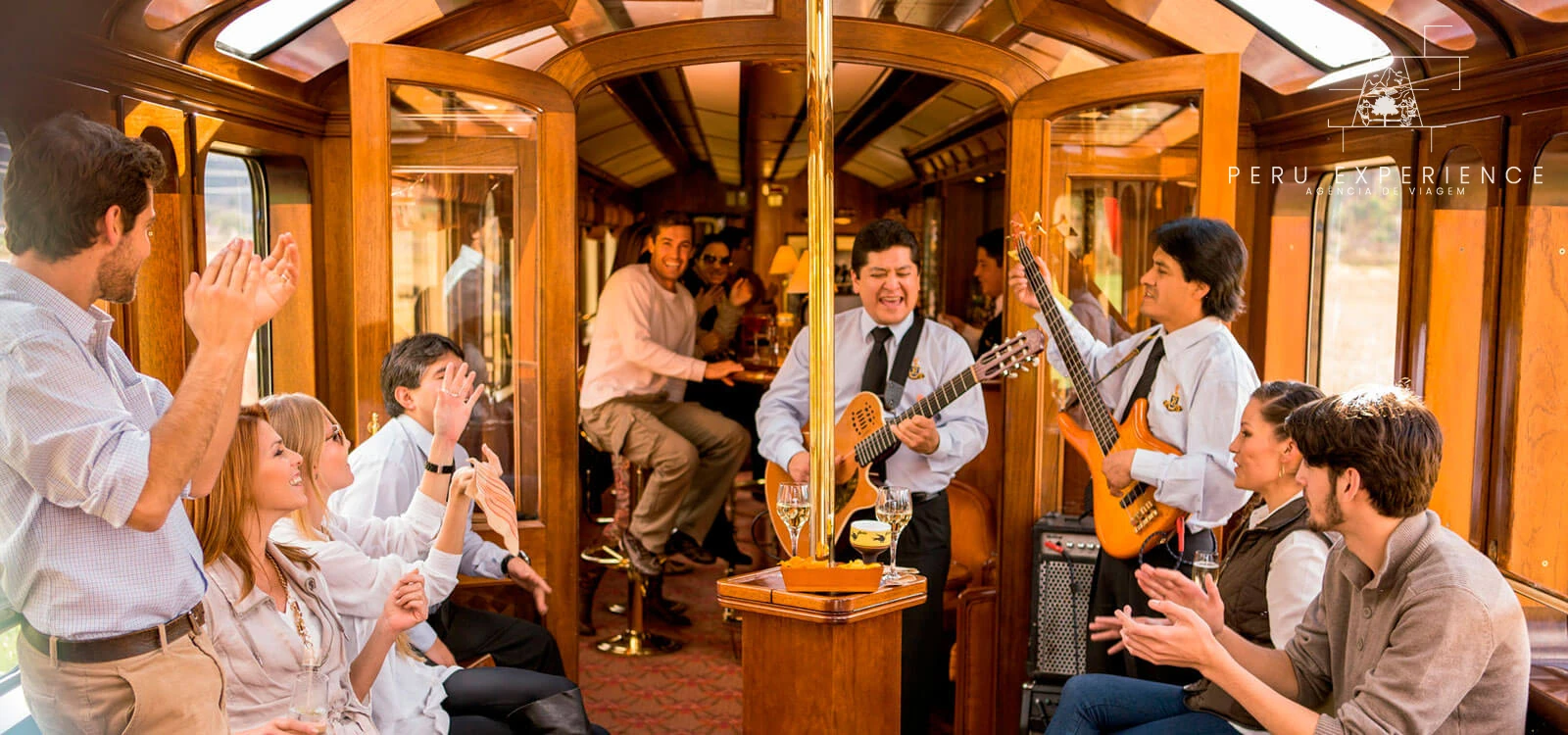 Músicos com violões se apresentam aos passageiros no interior do trem Hiram Bingham.